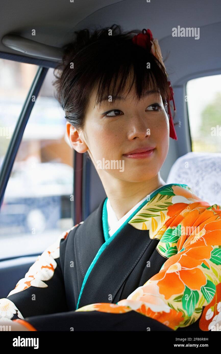 Schöne japanische Frau im Kimono auf dem Rücksitz des Taxis Stockfoto