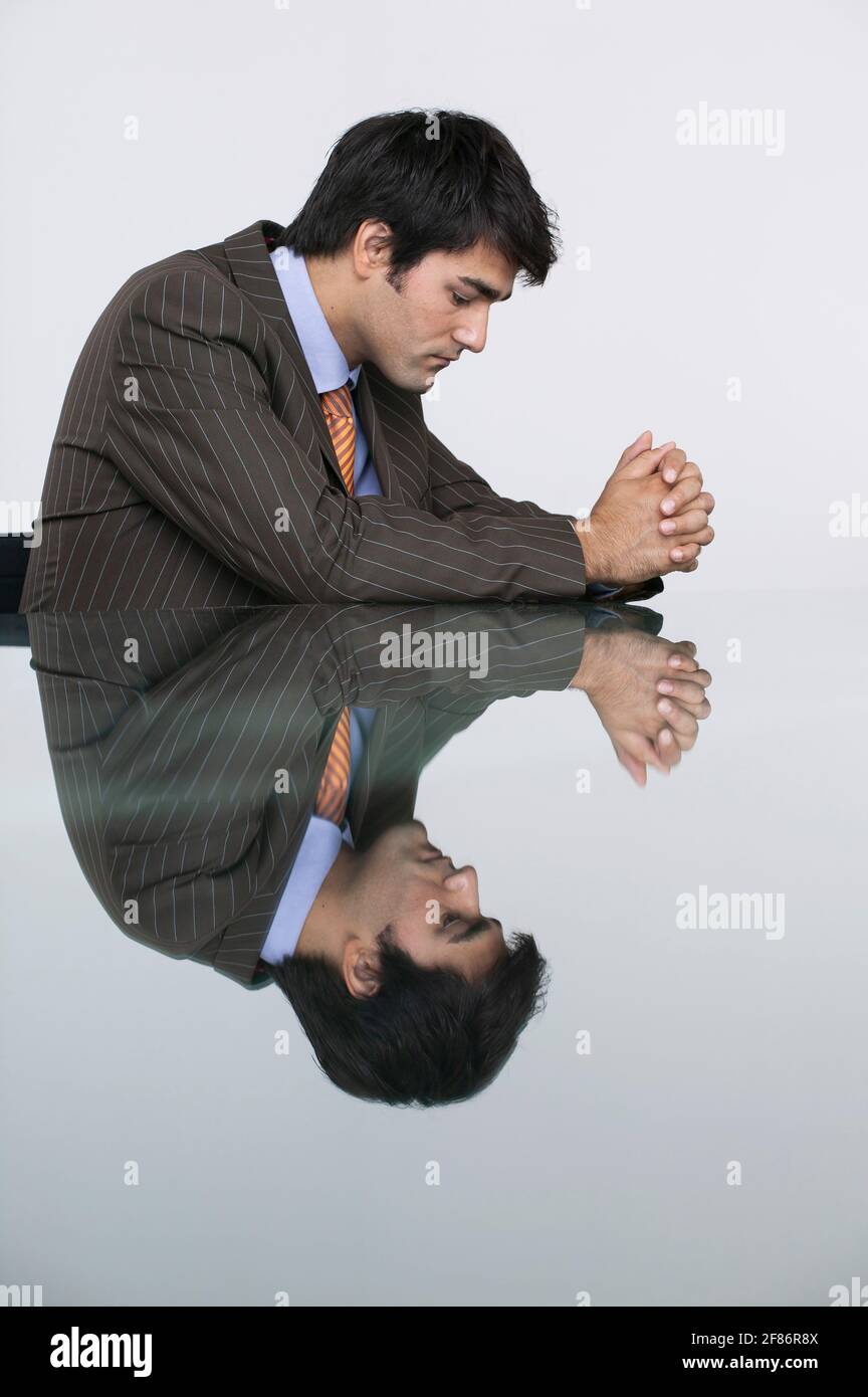 Spiegelung eines durchdachten Geschäftsmannes im Konferenzzimmertisch Stockfoto
