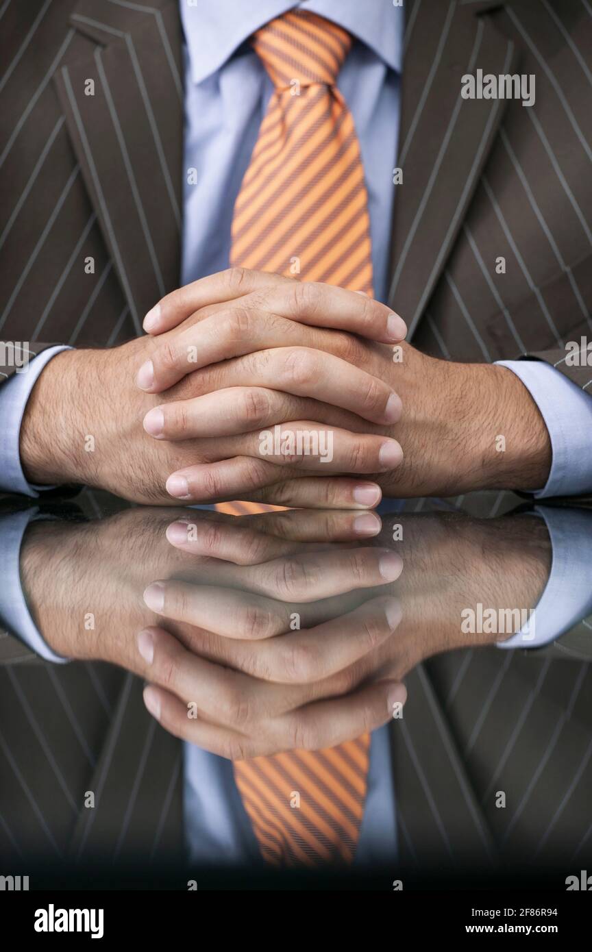 Nahaufnahme eines Geschäftsmannes mit Händen an einem reflektierenden Tisch Stockfoto