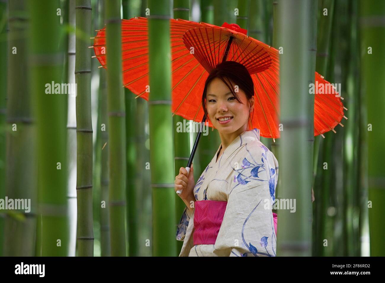 Portrait schöne junge Frau in Kimono mit Sonnenschirm zwischen Bambus Stockfoto