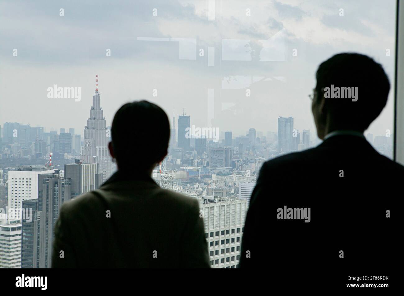 Geschäftsleute, die das Stadtbild von einem Bürohochhaus aus betrachten Stockfoto