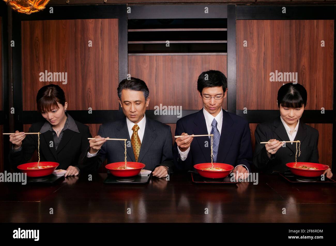 Japanische Geschäftsleute in Anzügen essen Ramen mit Essstäbchen in Restaurant Stockfoto