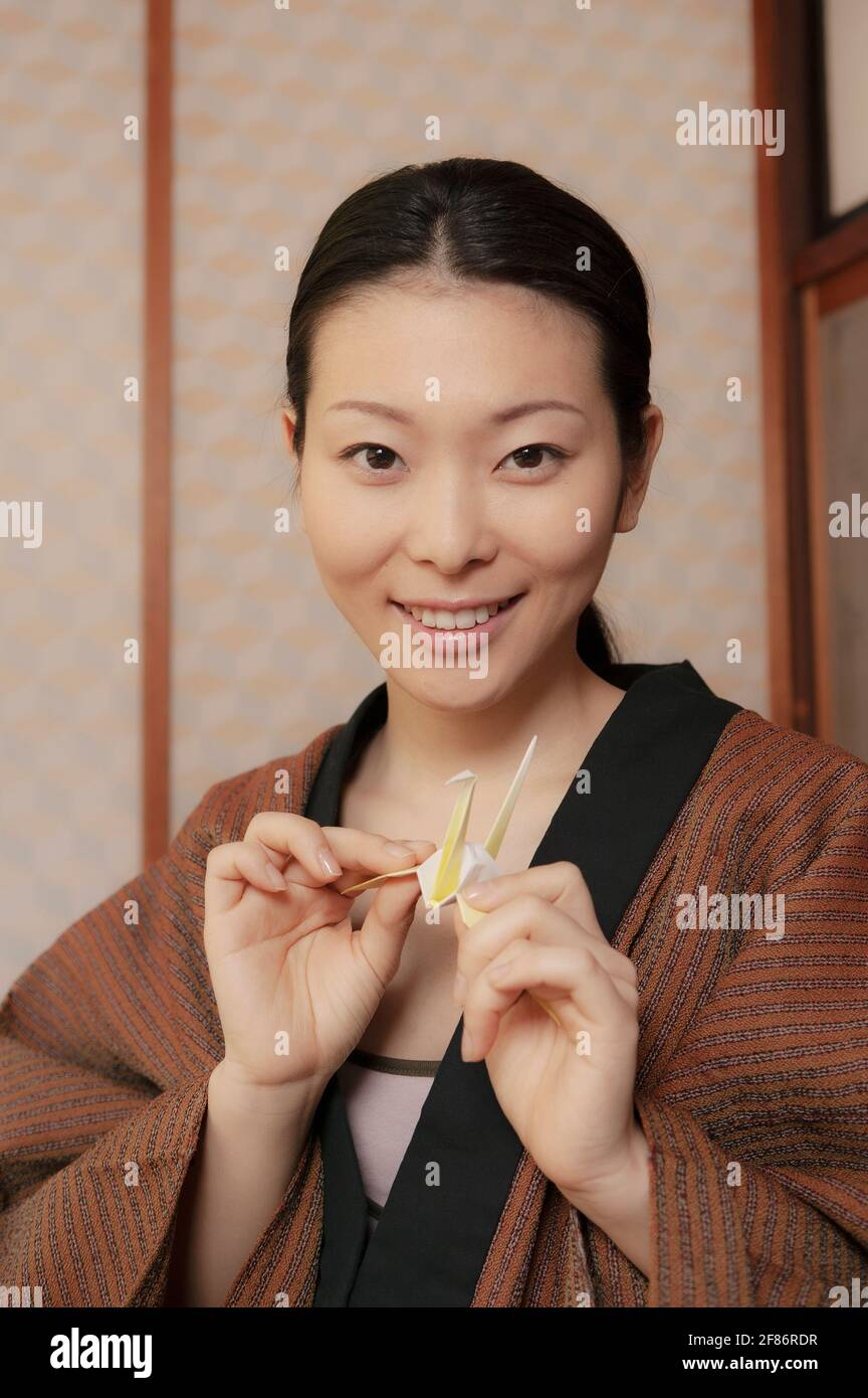 Portrait schöne junge Frau mit Origami-Papierkran Stockfoto