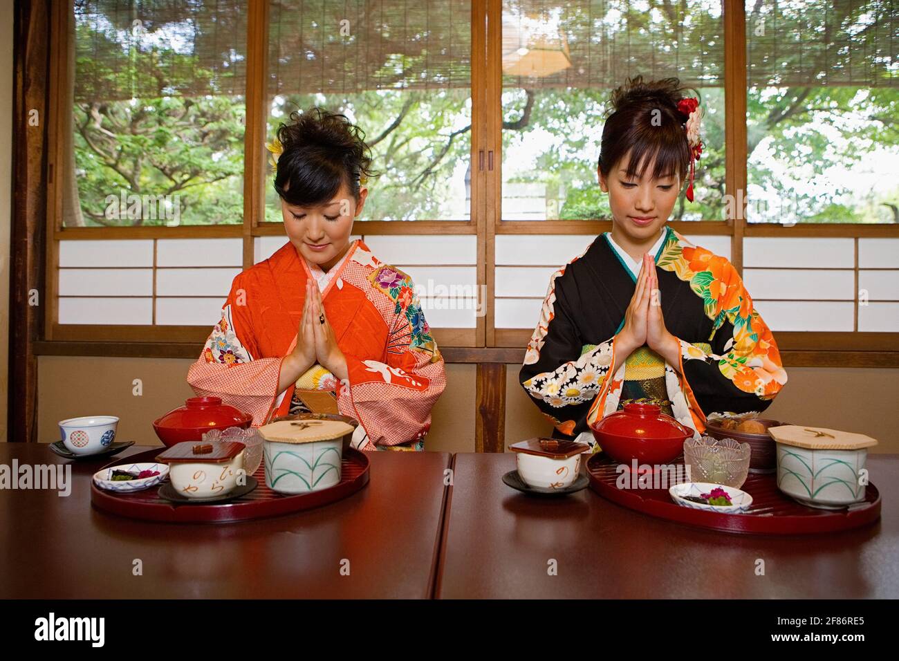 Junge Frauen in Kimonos beten beim Mittagessen im Restaurant Stockfoto