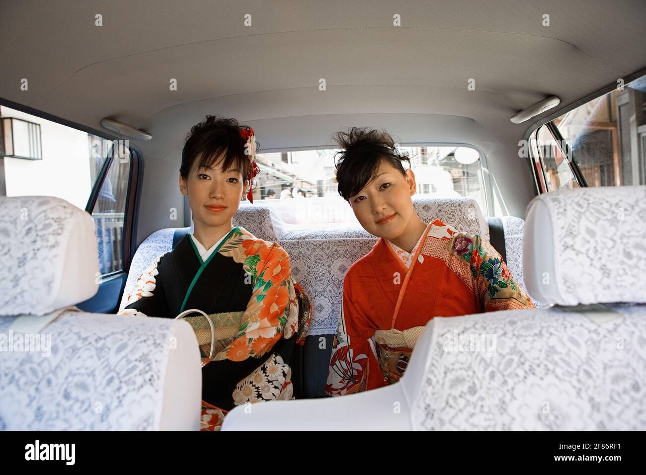 Porträt Japanische Frauen in Kimonos, die auf dem Rücksitz von reiten Auto Stockfoto