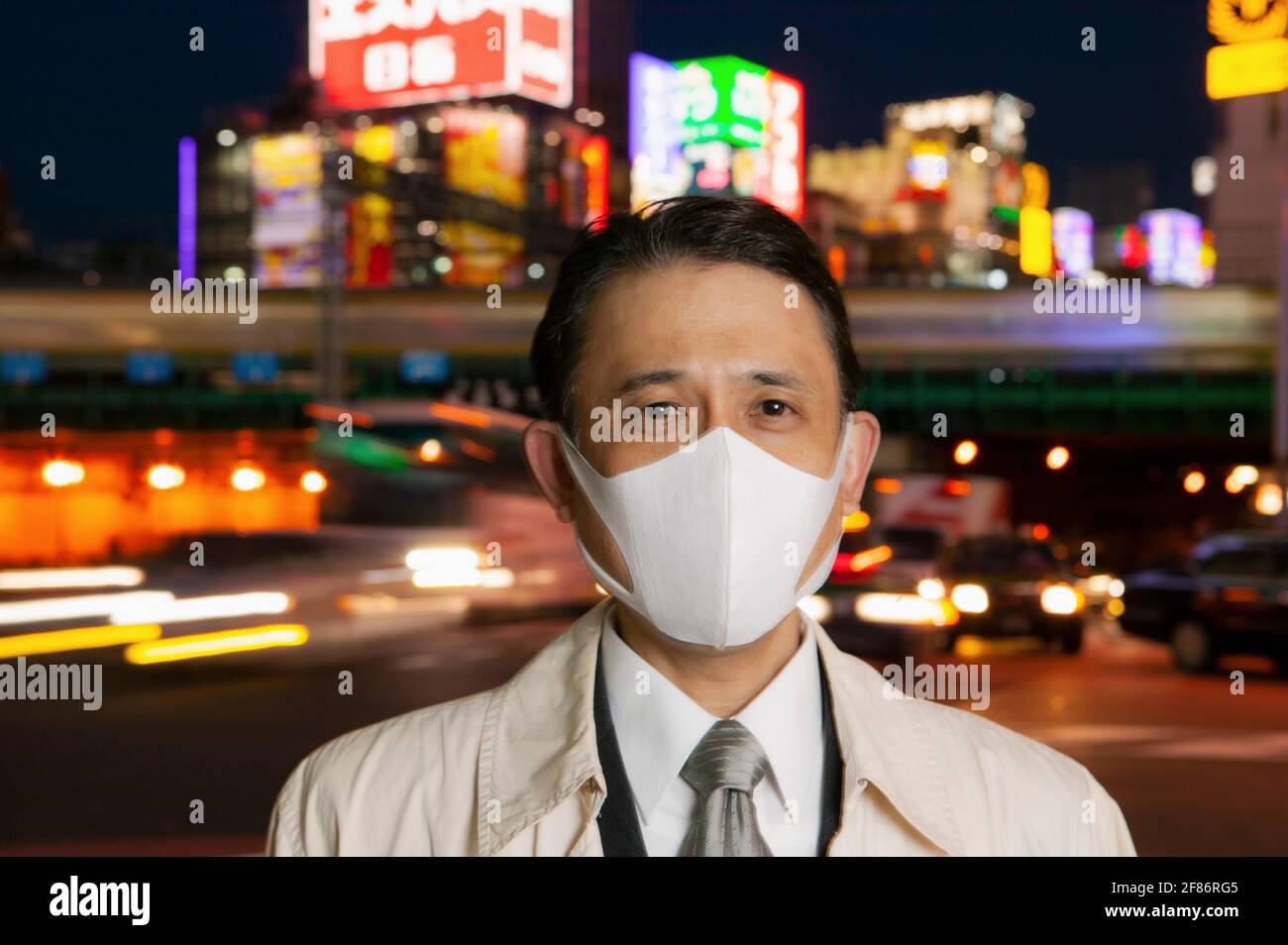 Portrait selbstbewusster Geschäftsmann in Gesichtsmaske in der Stadt bei Nacht, Tokio, Japan Stockfoto