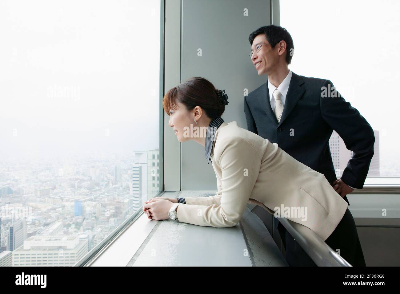 Geschäftsleute, die aus dem Hochhausfenster blicken Stockfoto