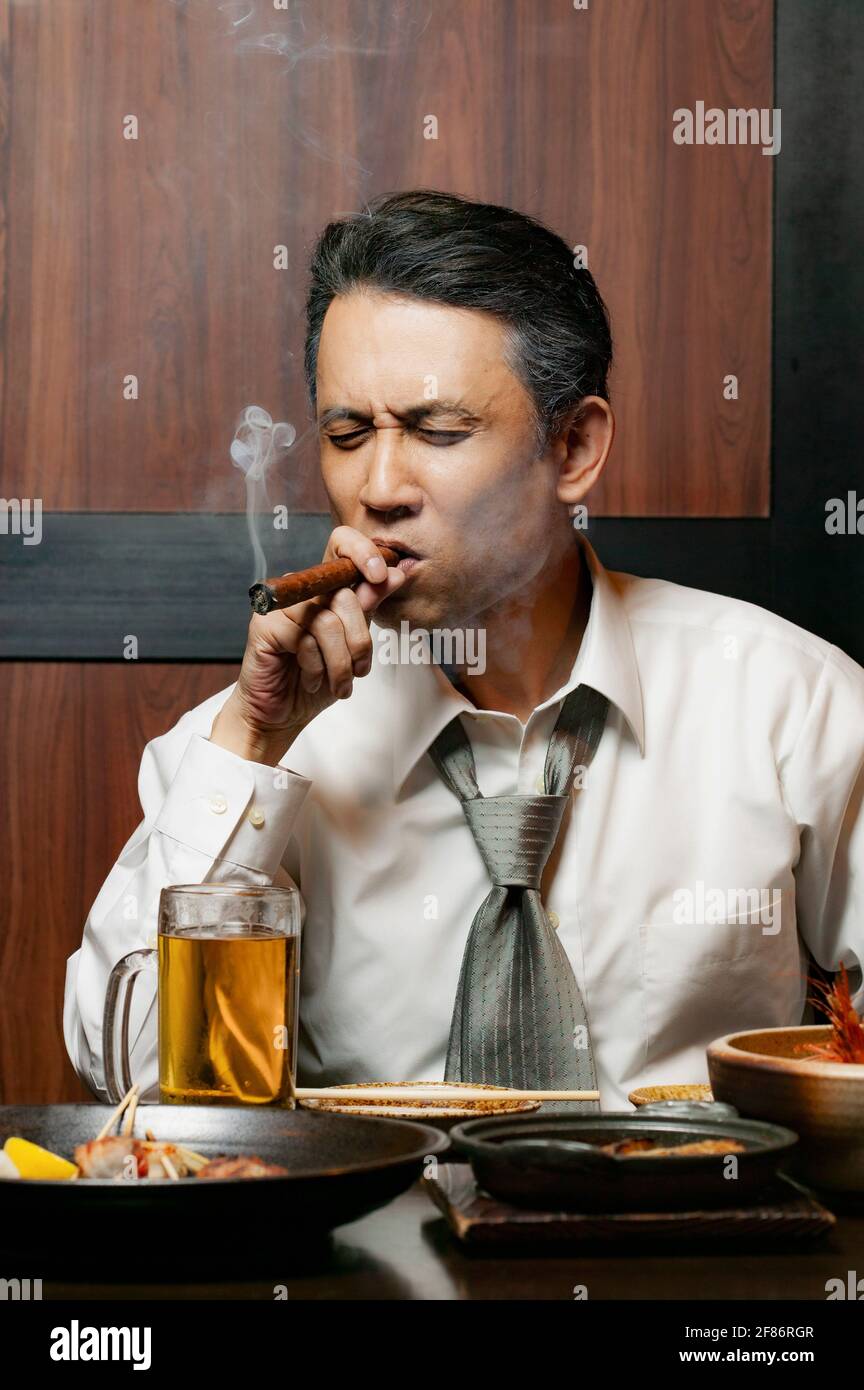 Geschäftsmann raucht beim Mittagessen im Restaurant Zigarre Stockfoto
