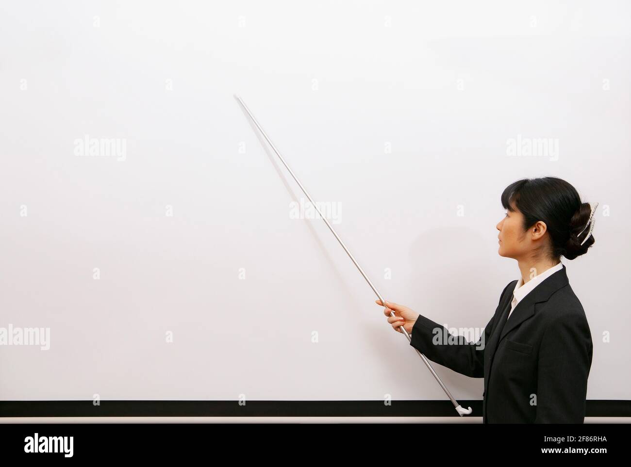 Geschäftsfrau führt Lektion mit Zeiger auf Whiteboard Stockfoto