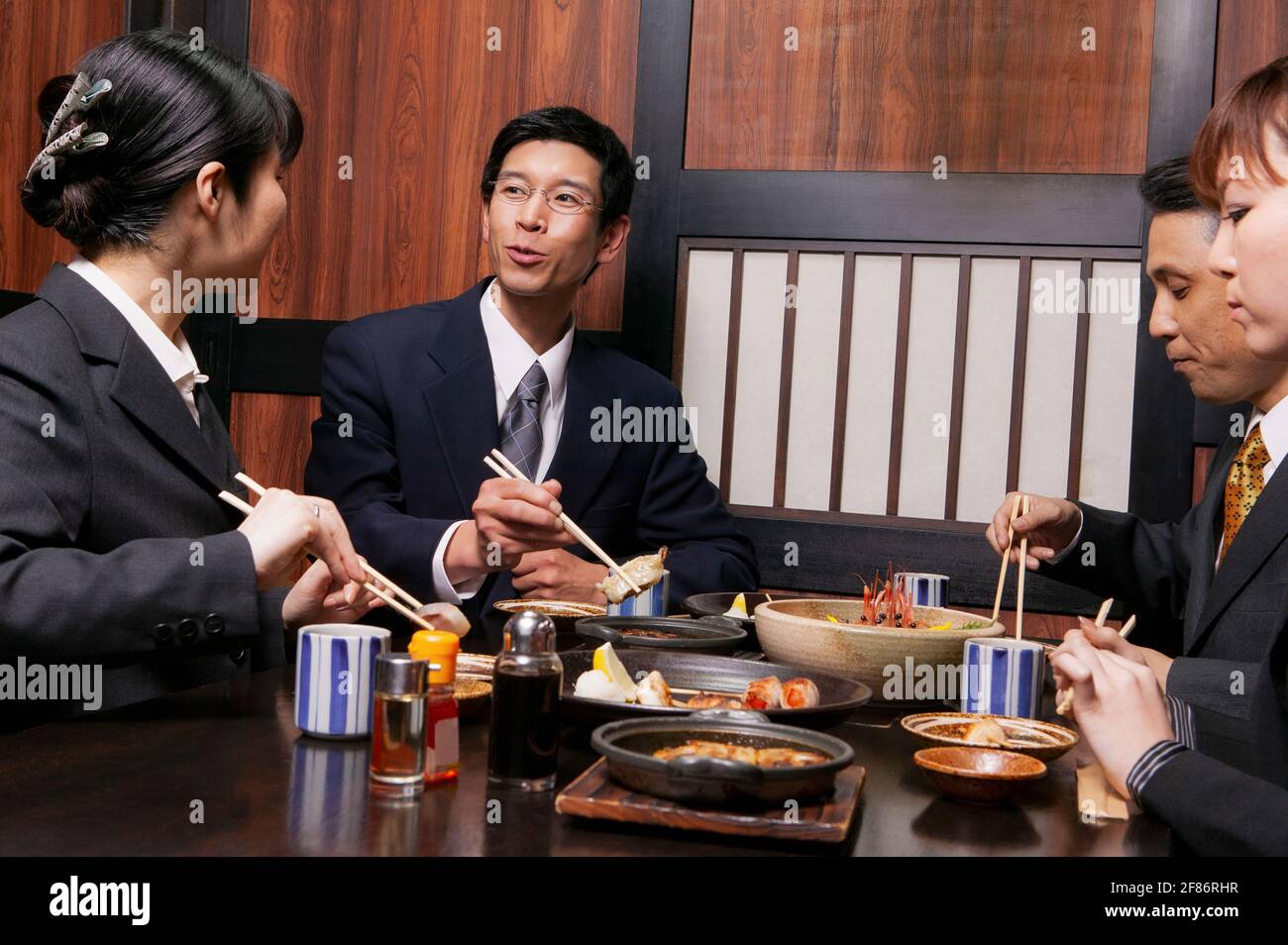 Geschäftsleute essen am Restauranttisch zu Mittag mit Essstäbchen Stockfoto