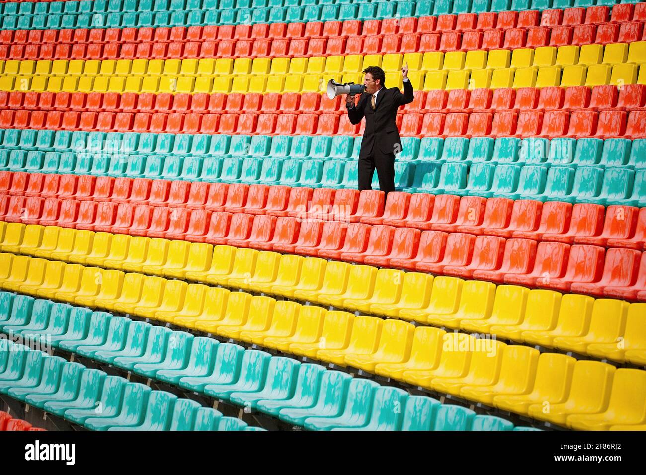 Mann mit Megaphon in farbenfrohen Fußballstadionsitzen Stockfoto