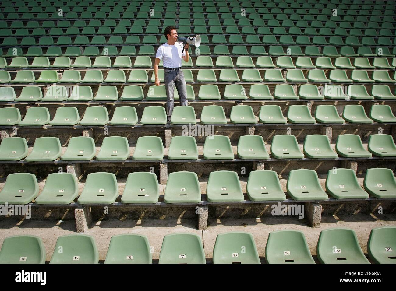Mann mit Bullhorn im Stadion mit grünen Sitzen Stockfoto
