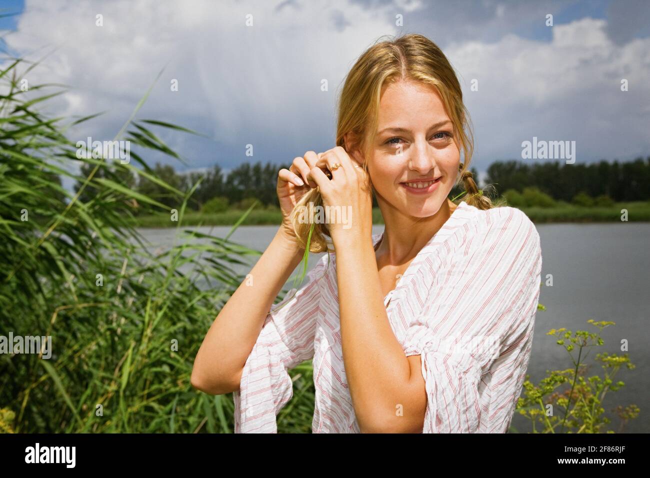 Portrait schöne junge Frau am sonnigen Seeufer Stockfoto