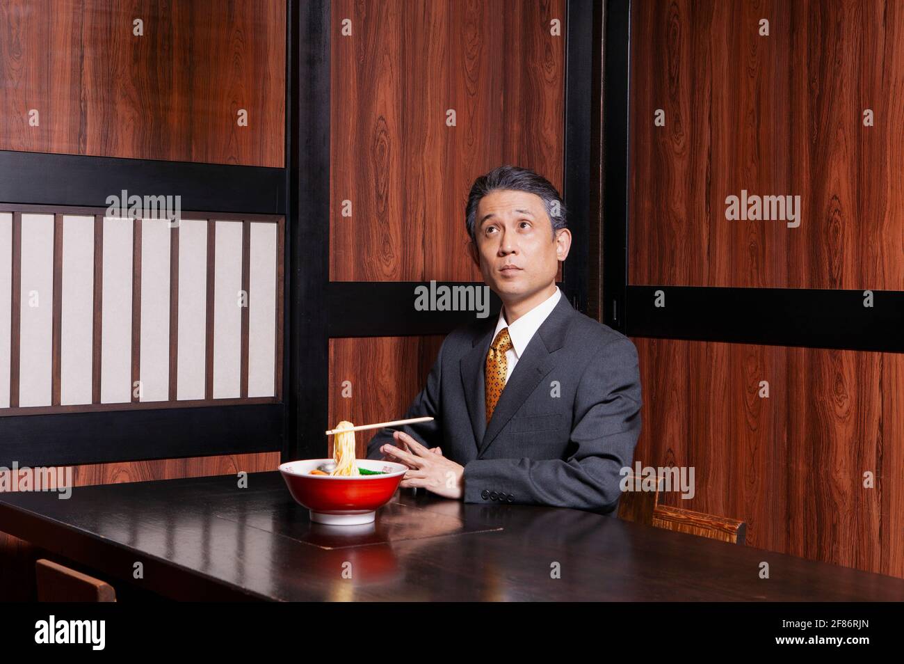 Geschäftsmann mit schwebendem Essstäbchen und Nudeln im Restaurant Stockfoto