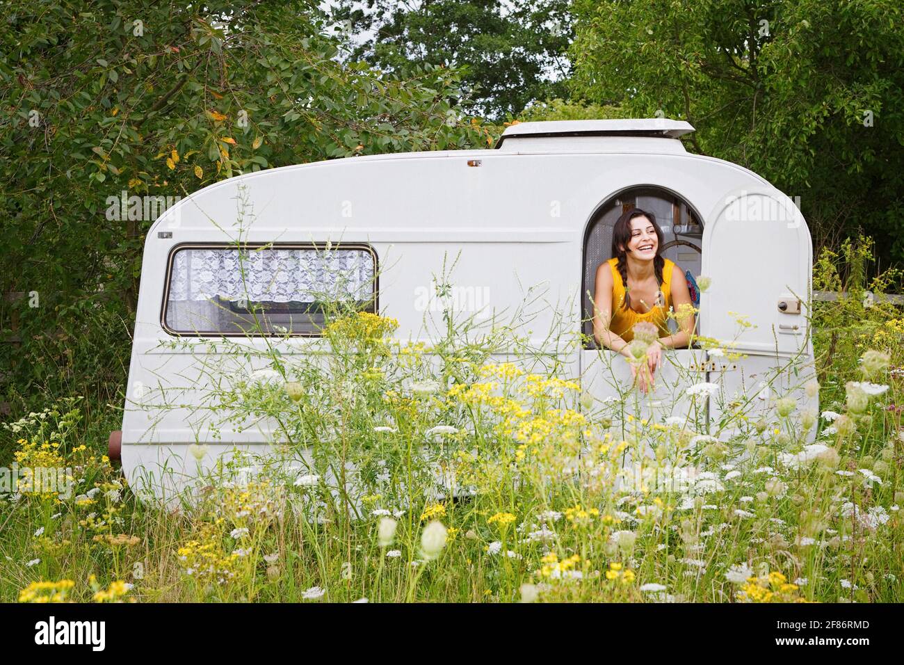 Glückliche junge Frau im Camper Trail auf der Wiese Stockfoto