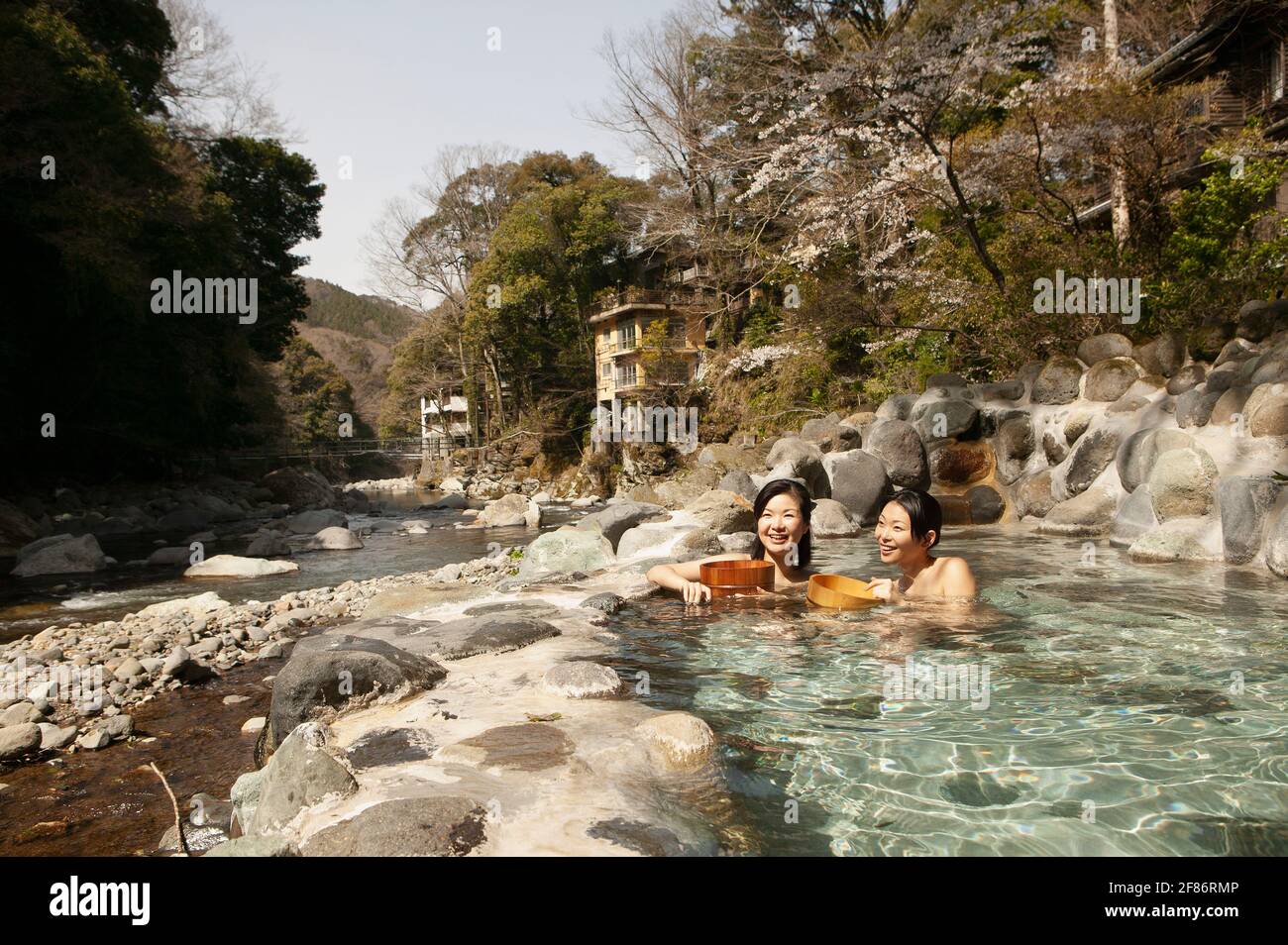 Glückliche junge Frauen, die im sonnigen Onsen Pool, Izu, Japan, baden Stockfoto