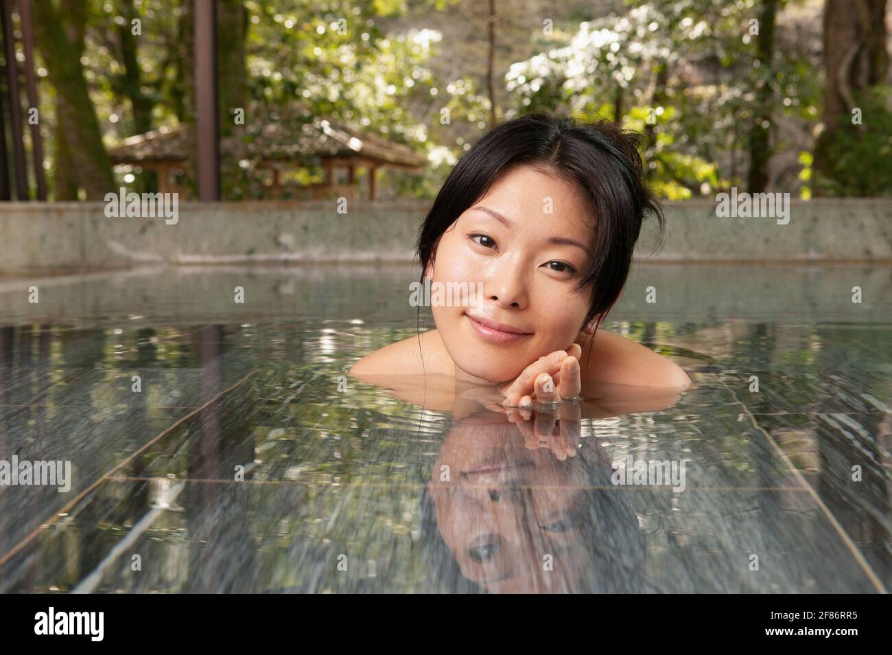 Portrait schöne junge Frau, die im Pool im ruhigen Onsen einweicht Stockfoto