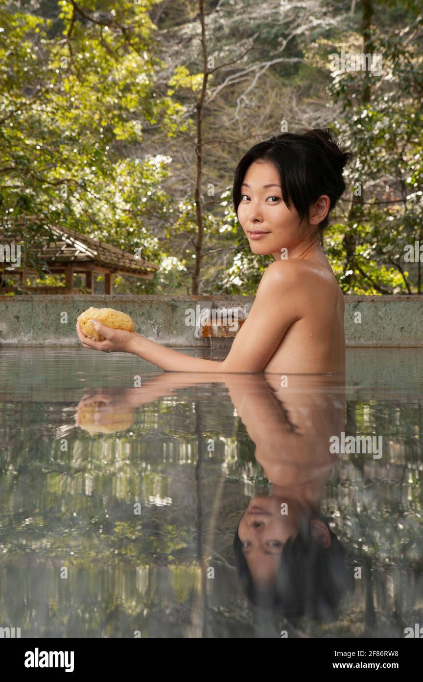 Portrait schöne nackte junge Frau mit Loofa im Pool an Onsen Stockfoto