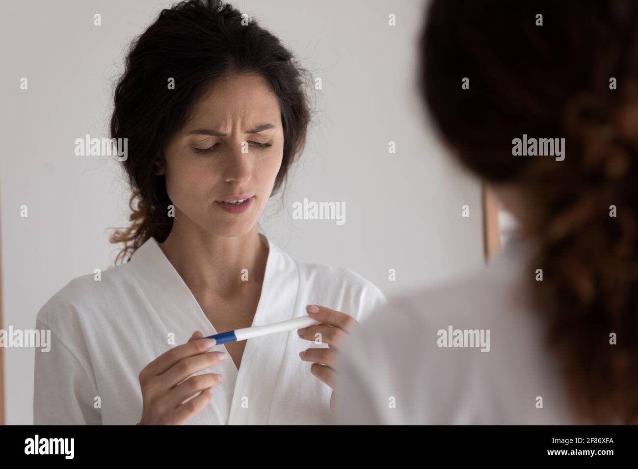 Nahaufnahme Spiegelung einer unglücklichen Frau, die einen Schwangerschaftstest durchgeführt hat Stockfoto