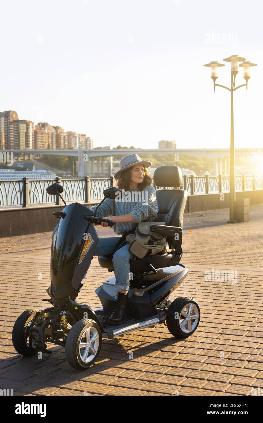 Frau Tourist Reiten ein vier Rad Mobilität Elektroroller auf einer Stadtstraße. Stockfoto