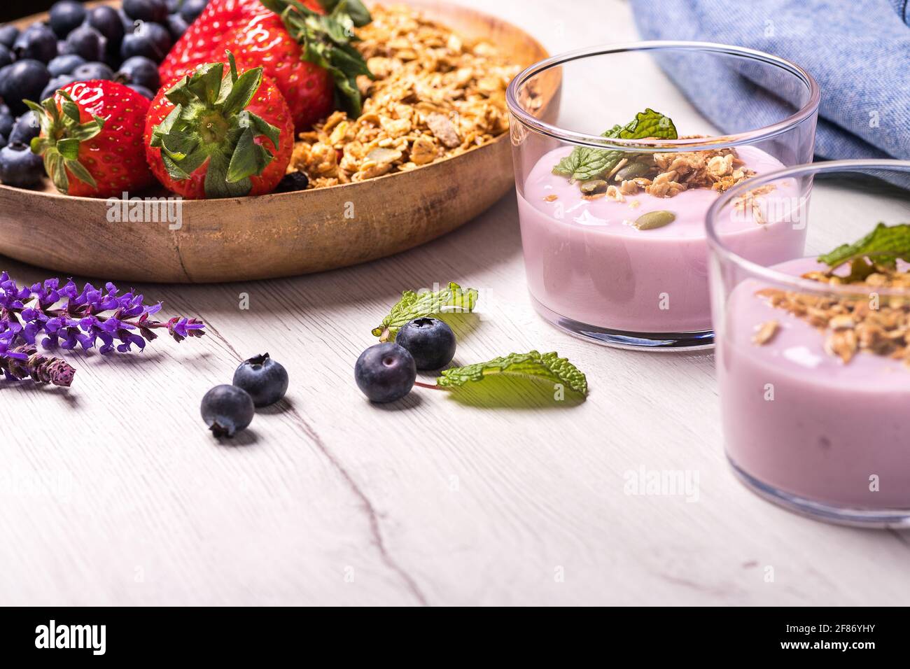 Natürlicher Joghurt mit frischen Beeren und Haferflocken. Gesundes Dessert.gesundes und natürliches Frühstück mit Heidelbeeren, Erdbeeren und Müsli mit Crea Stockfoto