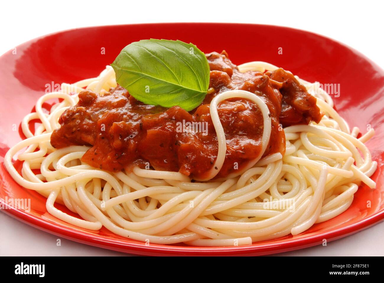 Spaghetti mit Tomatensauce auf rotem Teller, isoliert auf weißem Hintergrund Stockfoto Spaghetti mit Tomatensauce auf rotem Teller, isoliert auf weißem Hintergrund Stockfoto