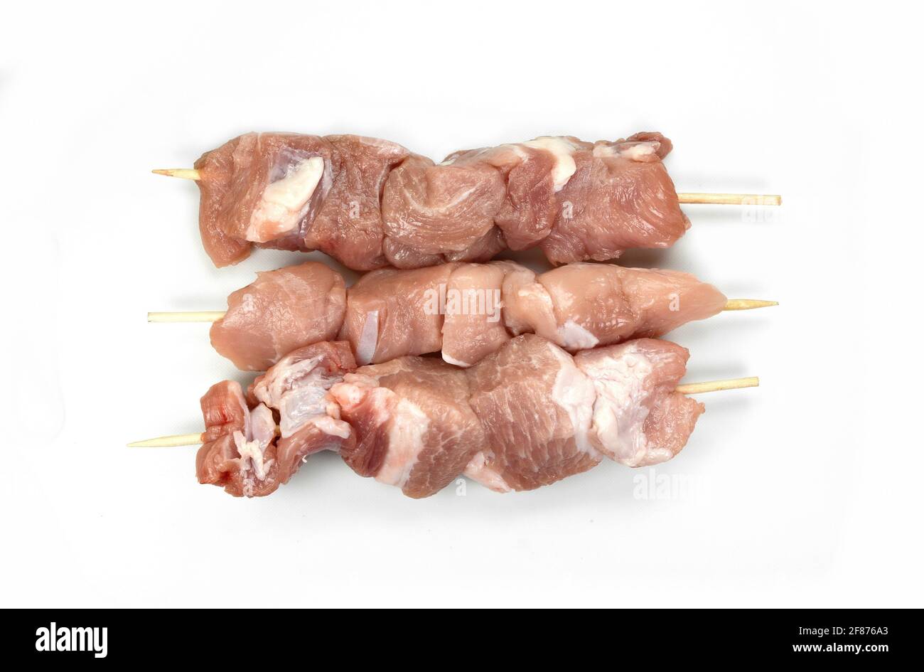 Roher Schweinekebab auf Weiß isoliert. Spieß mit rohem Fleisch isoliert auf weißem Hintergrund Stockfoto