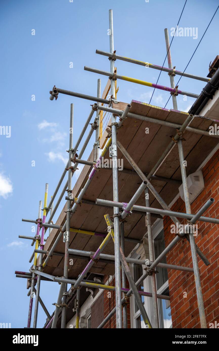 Gerüstmasten, die an der Seite eines britischen Hauses errichtet wurden Stockfoto