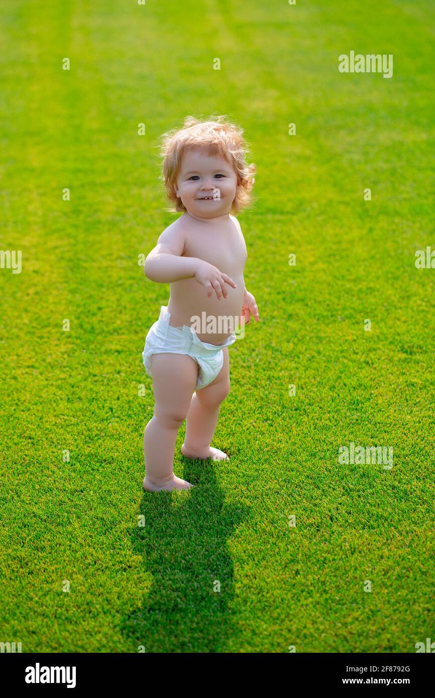 Nettes witziges lachendes Baby, das kriechen lernt und Spaß beim Spielen auf dem Rasen hat und den Sommer im Garten beobachtet. Glück und Harmonie im Familienleben. Stockfoto