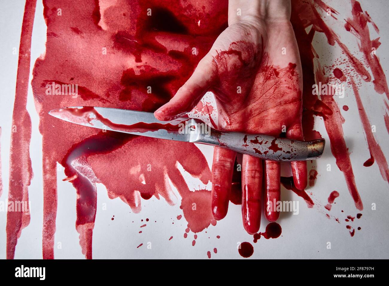 Eine blutige weibliche Hand hält ein blutiges Messer Stockfoto