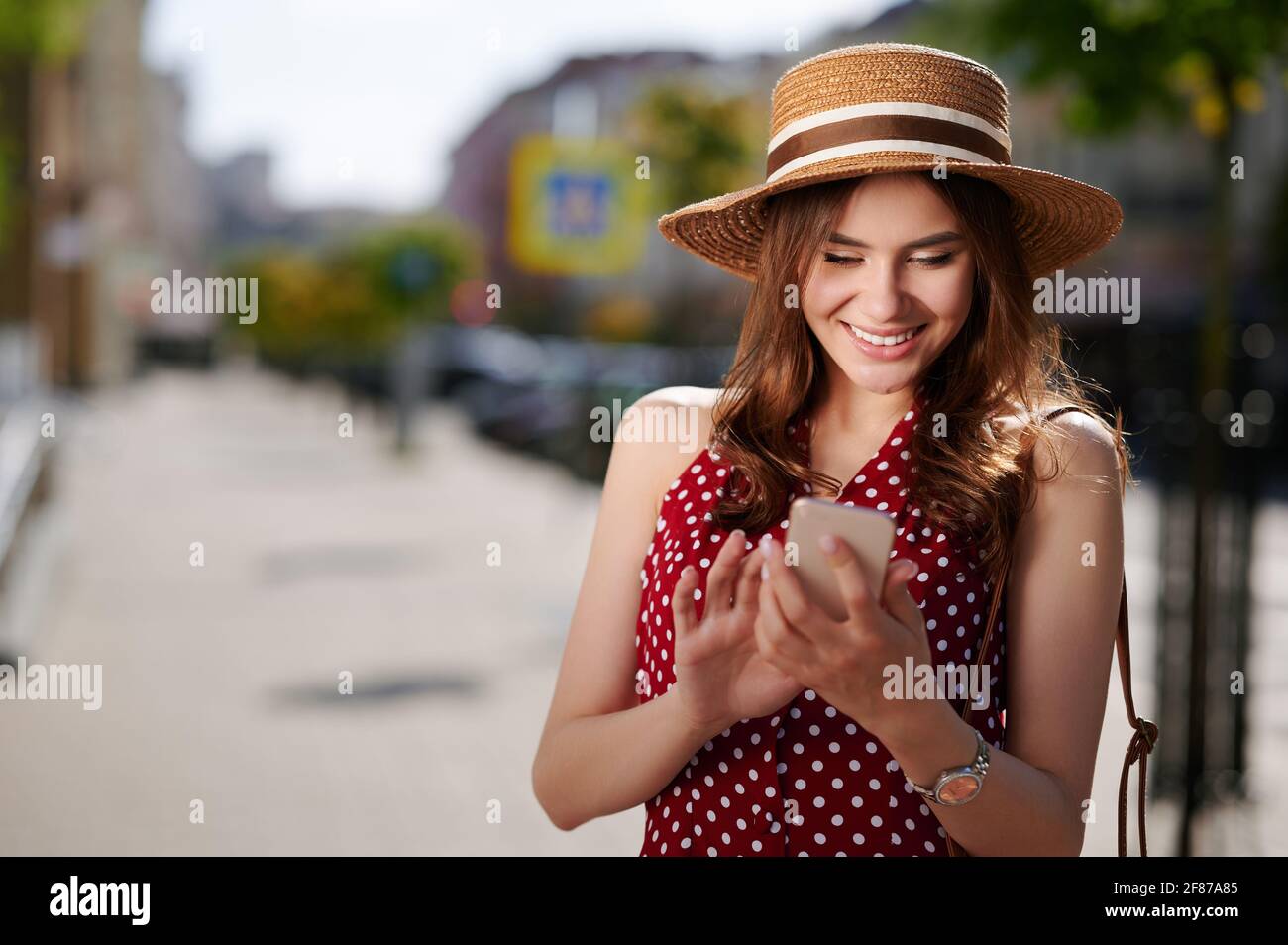 Glücklich lächelnde junge Frau mit Handy im Freien Stockfoto