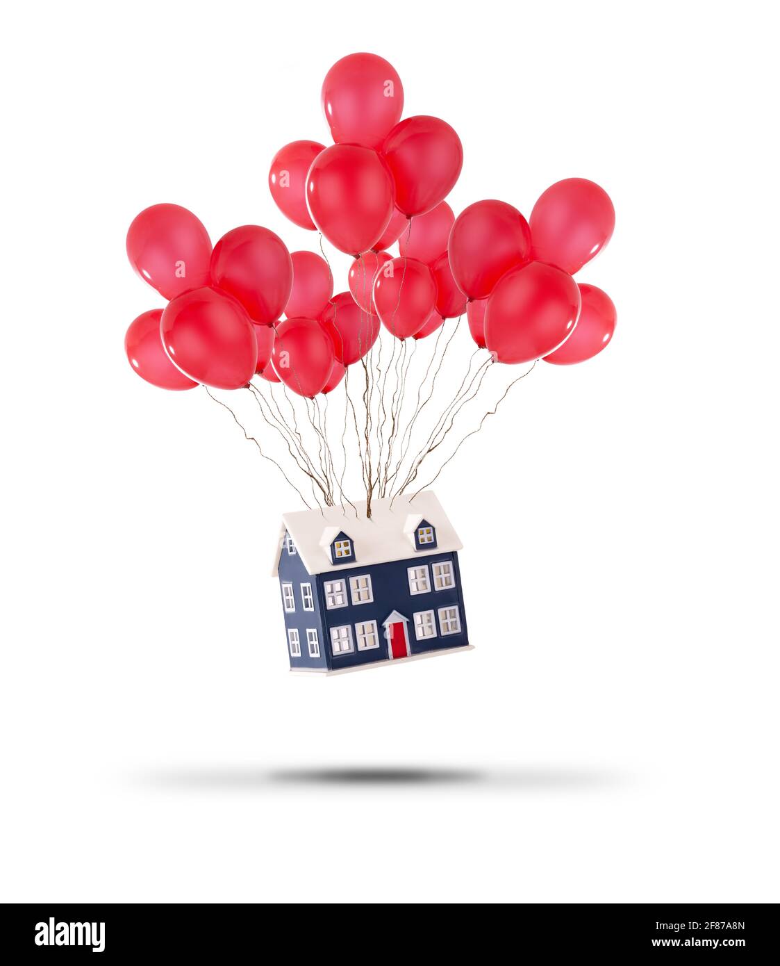 Das Spielzeughaus wurde mit roten Ballons auf weißem Hintergrund hochgehoben. Wohnungspreise steigen und Umzug nach Hause Konzept Stockfoto