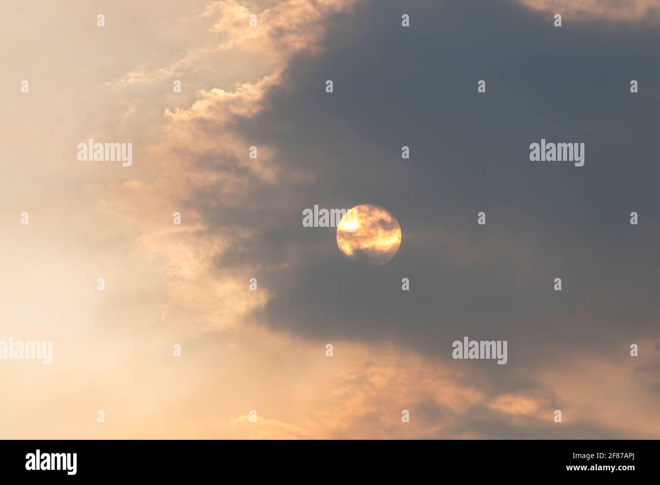 Sonnenuntergang mit Sonne hinter einer grauen Wolke und Rauch von Buschfeuern in der Nähe. Tamborine Mountain, Australien, Oktober 2019. Speicherplatz kopieren. Stockfoto