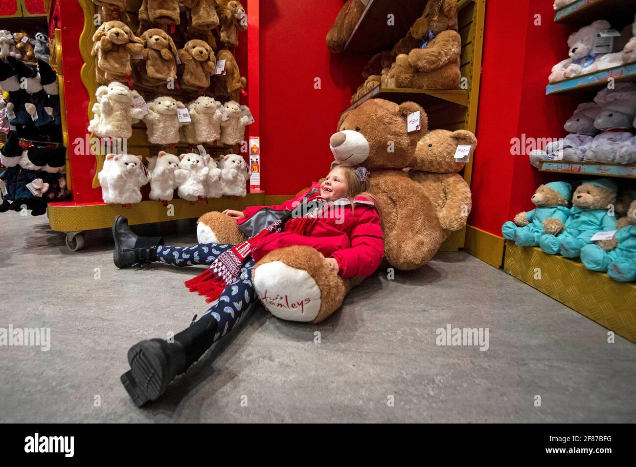 Lyla Stevens-Pierce, 7 Jahre alt, sitzt während der Wiedereröffnung des Spielzeugladens Hamleys in der Regent Street, London, auf einem riesigen Teddybären, während England mit der weiteren Lockerung der Sperrbeschränkungen einen weiteren Schritt zurück in Richtung Normalität unternimmt. Bilddatum: Montag, 12. April 2021. Stockfoto