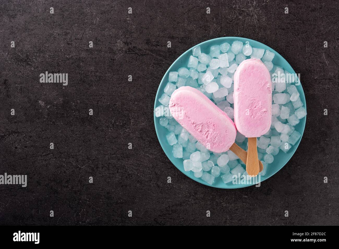 Erdbeerpopsicles und zerkleinertes Eis auf schwarzem Schiefer-Hintergrund Stockfoto
