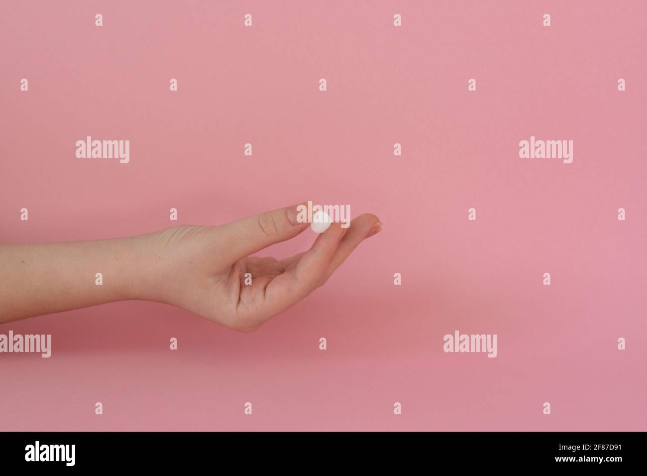 Vitamintablette in der Hand einer Frau, rosa Hintergrund Stockfoto