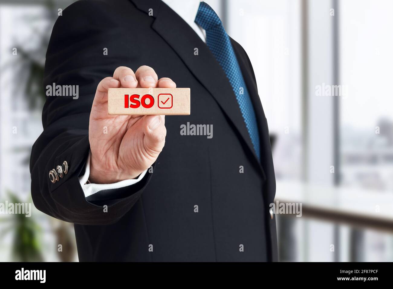 Businessman zeigt einen Holzblock mit dem Wort ISO mit Checkbox-Symbol. ISO-Normen Zertifizierung in Business Industry Konzept. Stockfoto