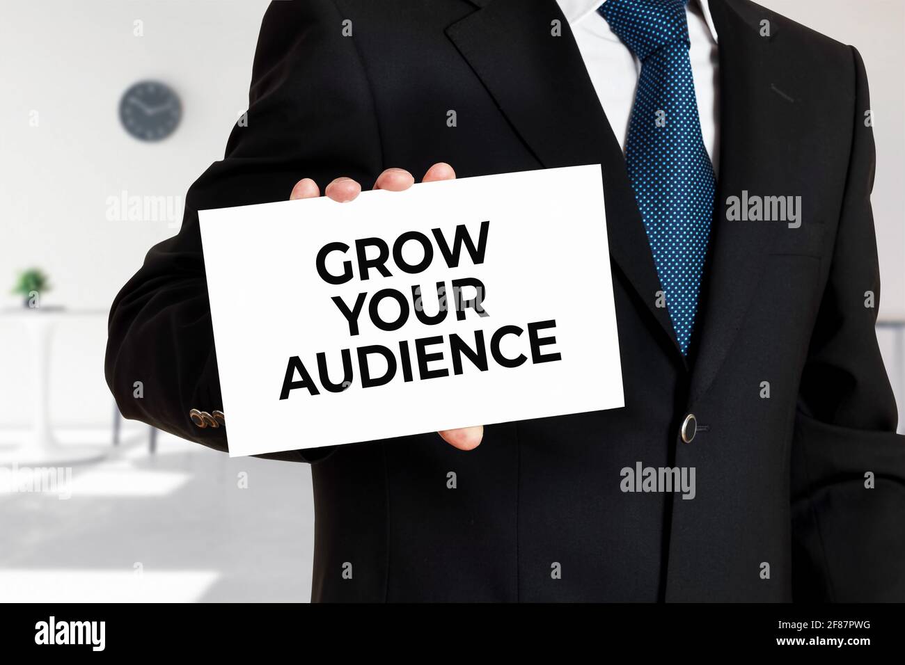 Geschäftsmann hält eine Karte mit der Nachricht wachsen Sie Ihr Publikum. Geschäftsmarketing-Konzept. Stockfoto