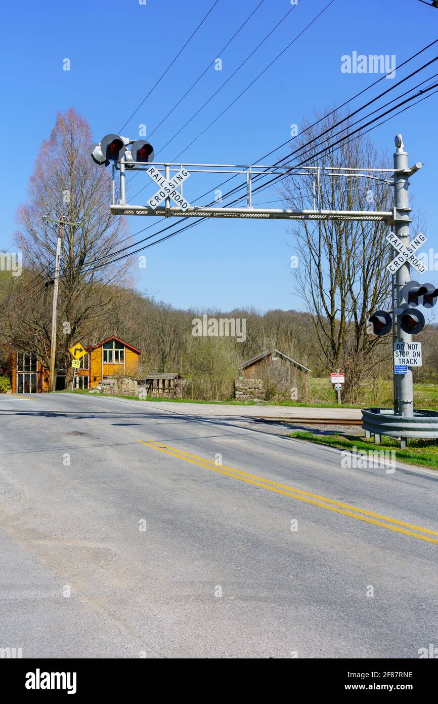 Embreeville, PA, USA - 6. April 2021: Ein Eisenbahnübergang mit elektrischen Überkopfwarnleuchten im ländlichen Chester County, PA. Stockfoto