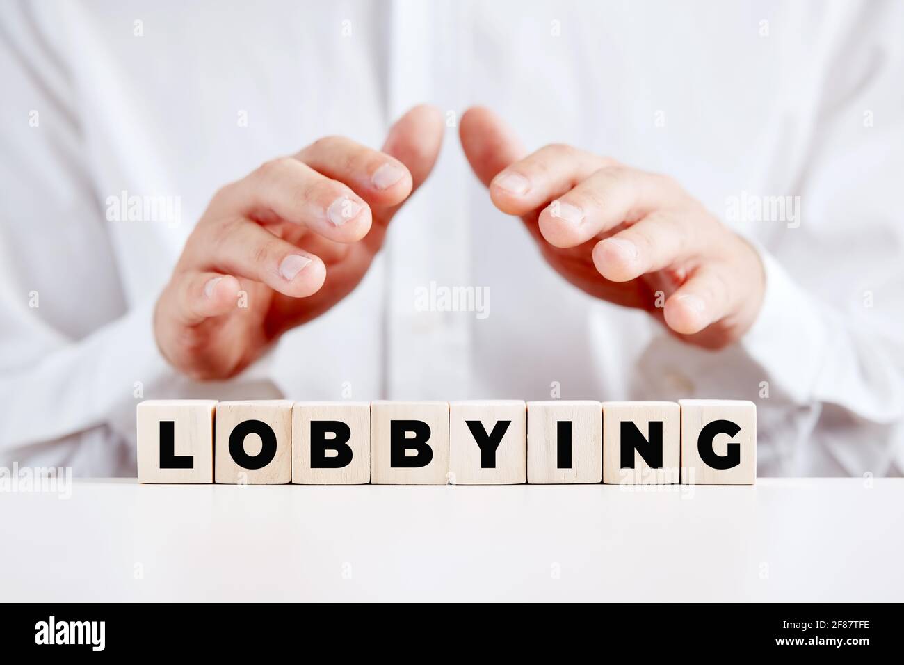 Geschäftsmann hält seine Hände über die Holzwürfel mit dem Wort Lobbying. Einfluss und Zugang im Politikkonzept. Stockfoto