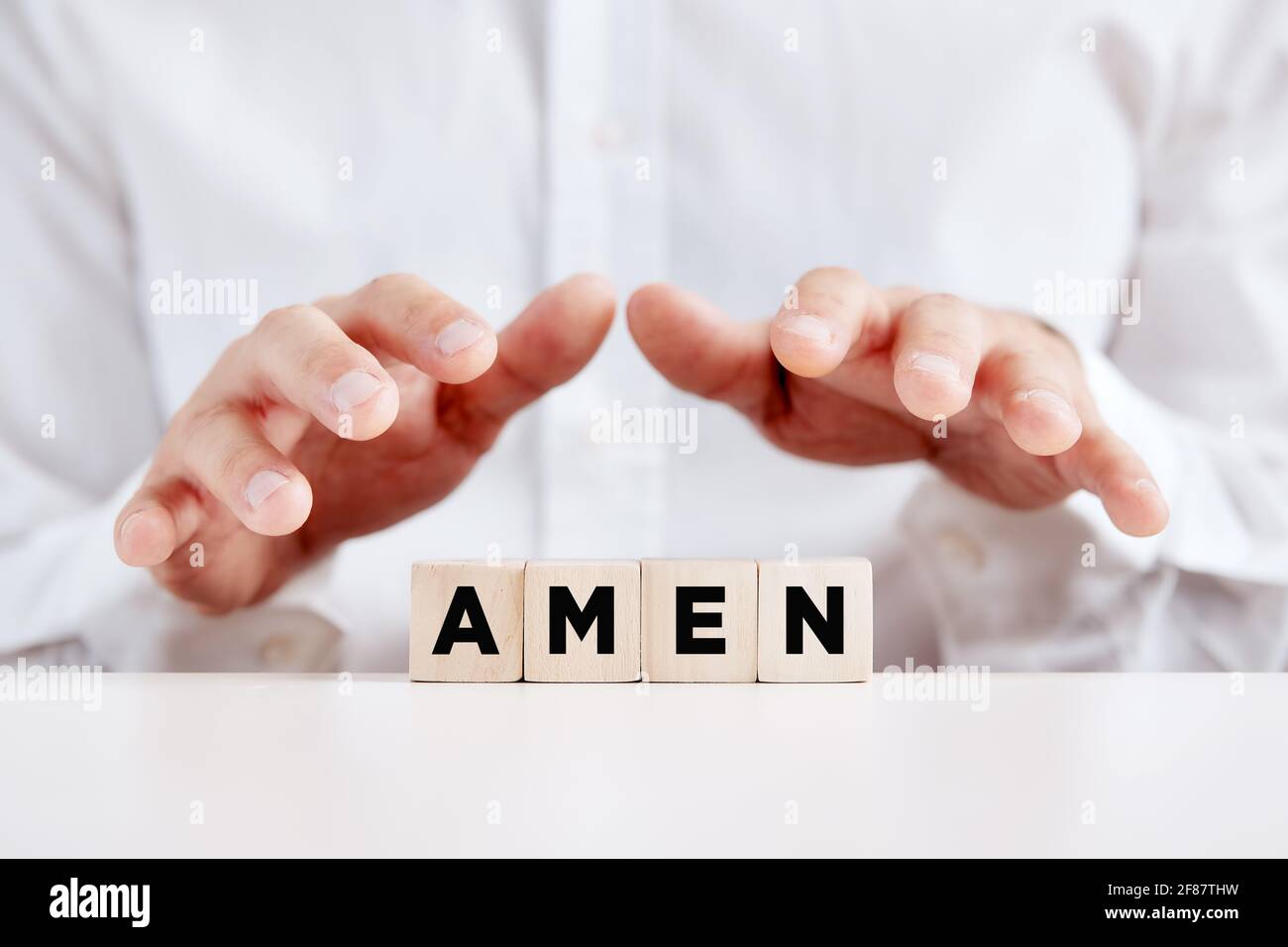 Der christliche Mann hält seine Hände mit dem Wort amen über die Holzwürfel. Stockfoto