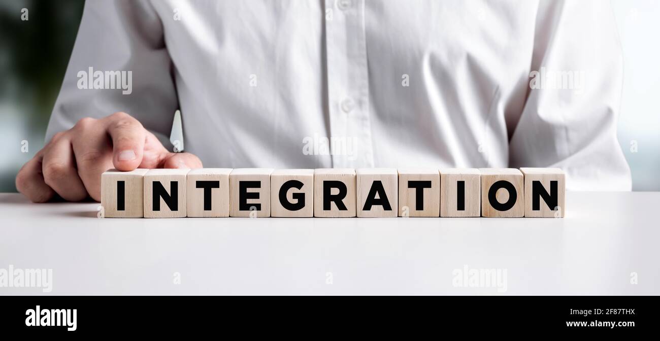 Geschäftsmann drückt mit dem Wort Integration den Finger auf die Holzwürfel. Konzept der Allianz, Partnerschaft, Fusion oder Teamwork-Einheit. Stockfoto