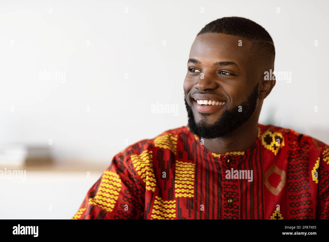 Nahaufnahme eines glücklichen jungen afrikanischen Mannes im Tribal-Hemd Wegschauen Stockfoto