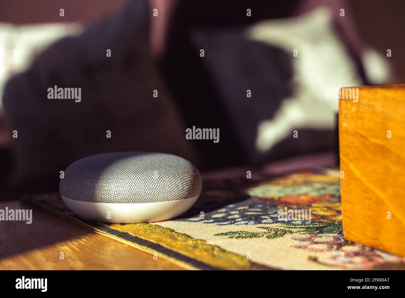 Sprachgesteuerter intelligenter Lautsprecher mit einer Frau im Hintergrund in einer Innenraumumgebung. Intelligentes AI-Lautsprecherkonzept Stockfoto