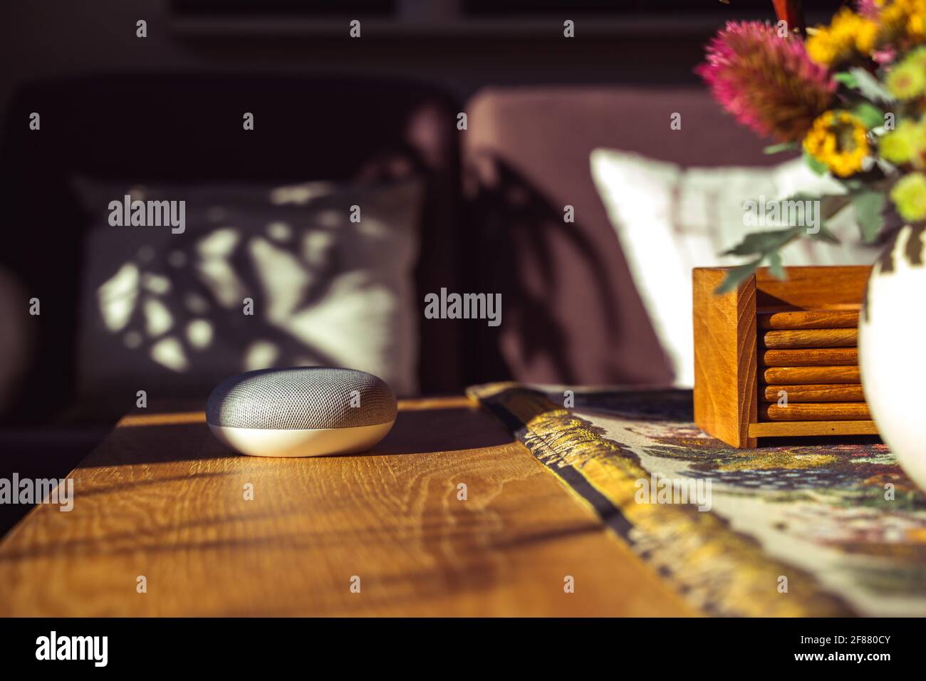 Sprachgesteuerter intelligenter Lautsprecher mit einer Frau im Hintergrund in einer Innenraumumgebung. Intelligentes AI-Lautsprecherkonzept Stockfoto