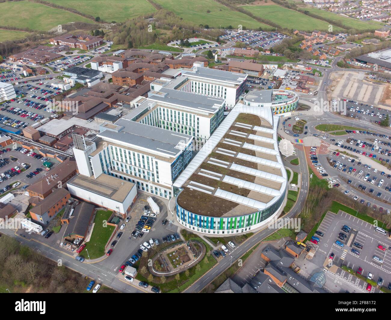 Modernes medizinisches Krankenhausgebäude der Stadt NHS mit einzigartigem Design, gebogener Front, grün, blau, weiß und aqua-minimalistischem, symmetrischem Layout. Stockfoto