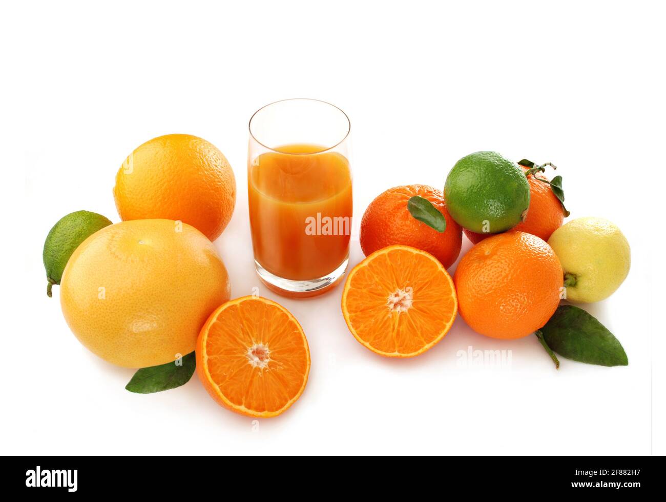 Verschiedene Zitrusfrüchte und ein Glas frischen Saft, erfrischendes gesundes Getränk, isoliert auf weißem Hintergrund Stockfoto