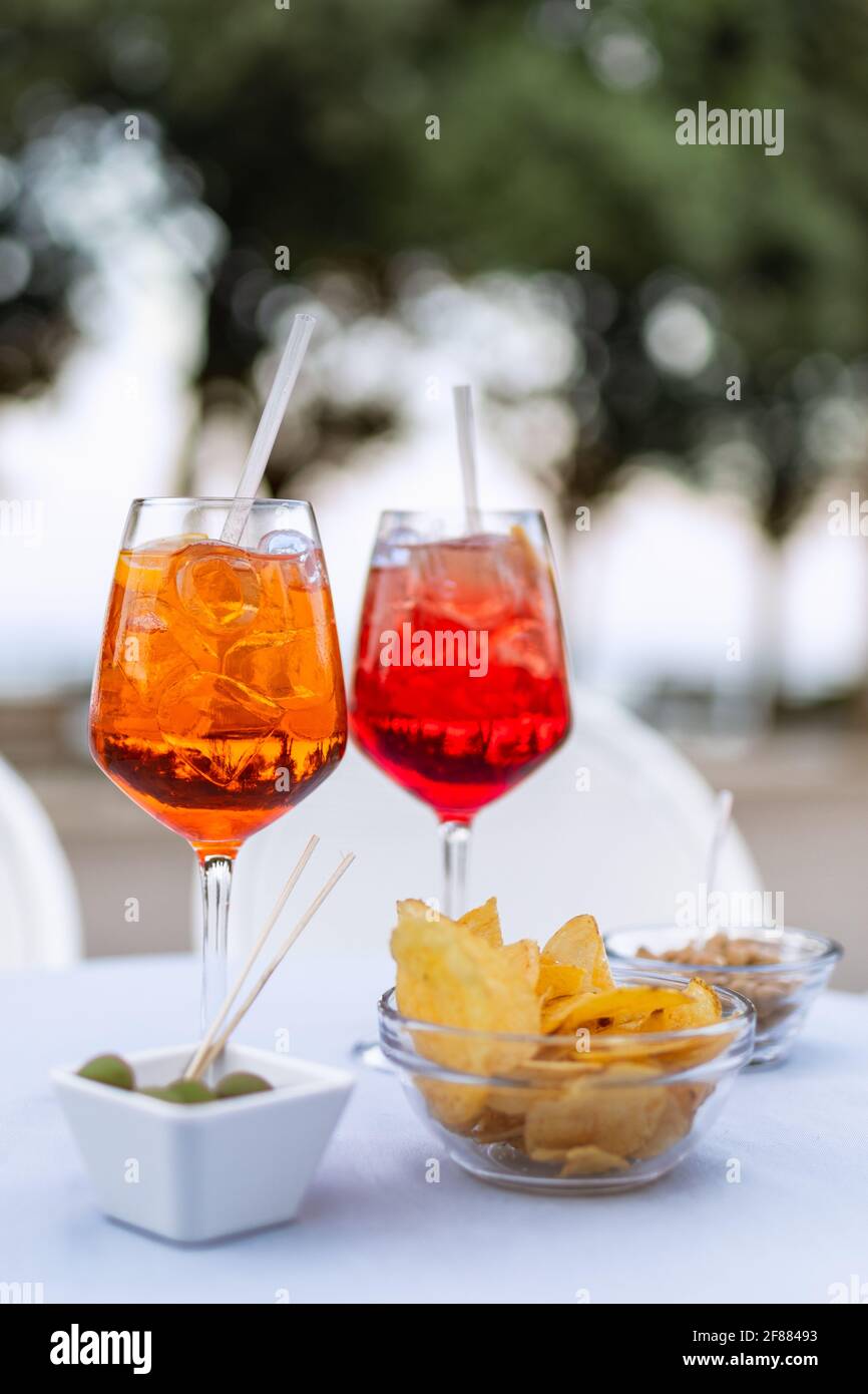 Zwei erfrischende italienische Cocktails mit Snacks auf dem Tisch (Vertikales Foto) Stockfoto