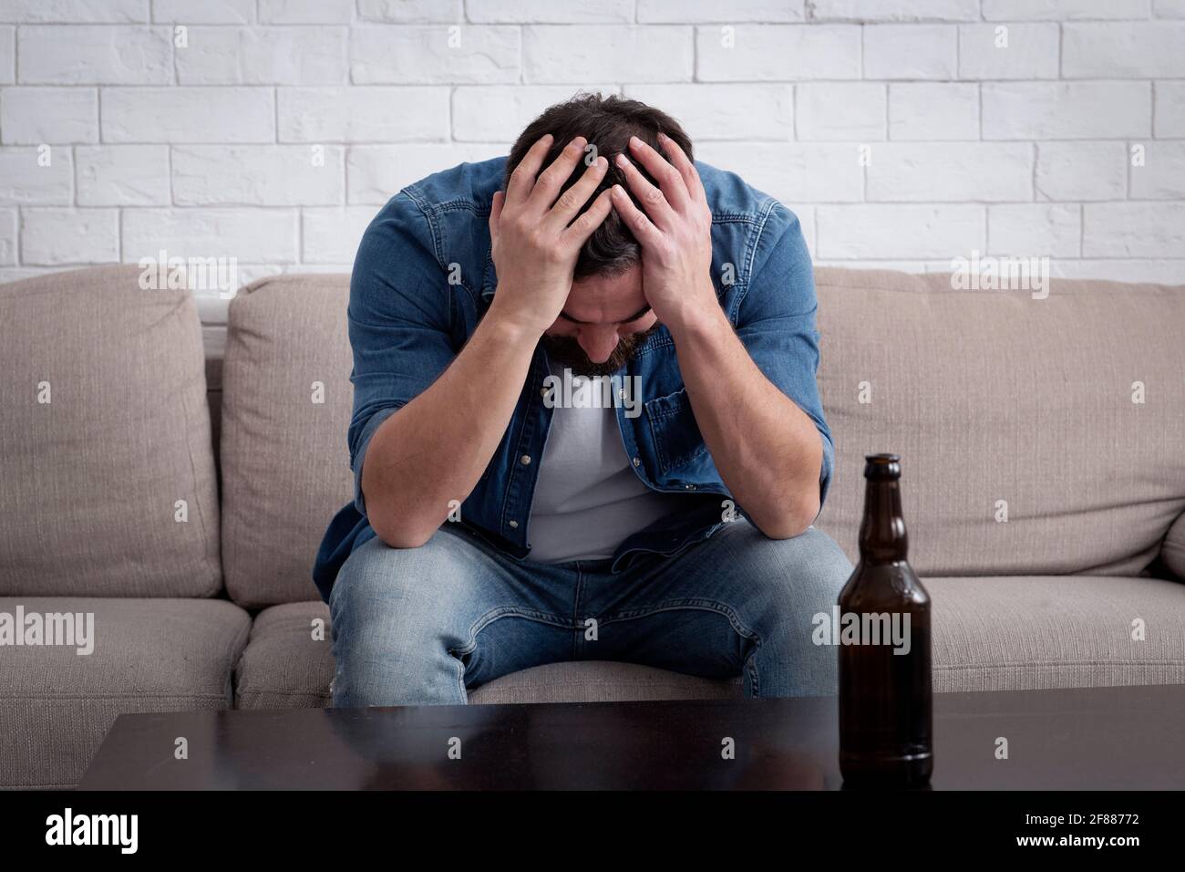 Schwäche, Depression, sucht und Alkoholismus. Millennial verärgert Mann auf dem Sofa sitzen Stockfoto