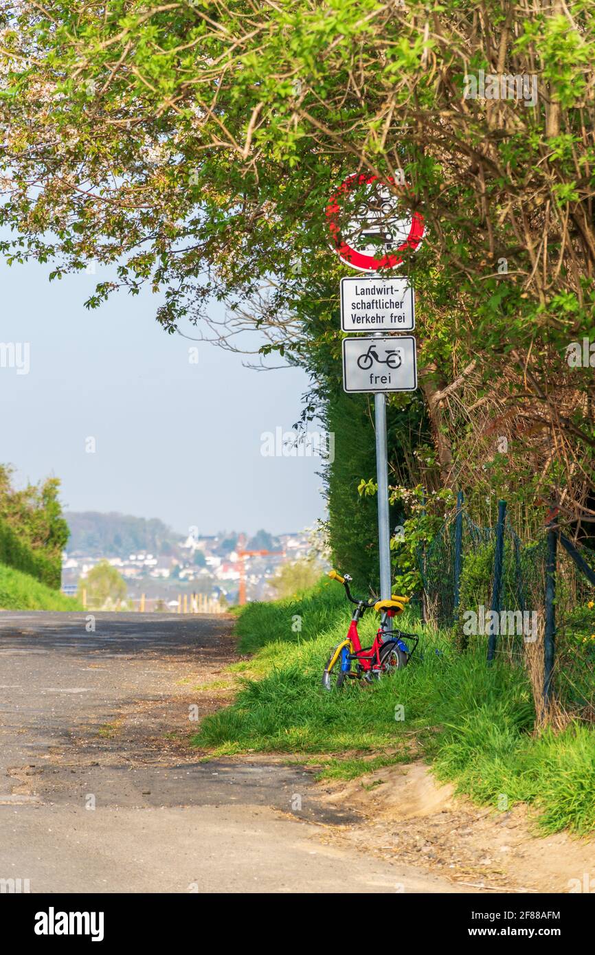 Das Fahrrad eines kleinen Kindes parkte an einem Verkehrsschild mit deutschem Text, auf dem steht: 'Nein Durchgangsverkehr. Freier landwirtschaftlicher Verkehr. Mopeds allowed“. Stockfoto